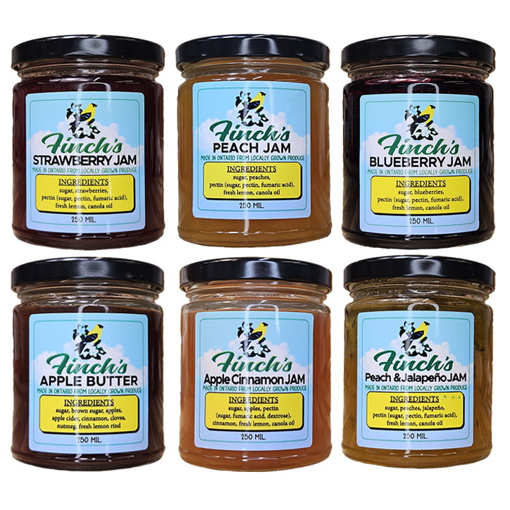 6 jam jars with 3 above and 3 overlapping. Blueberry Jam, Apple Butter, Apple Cinnamon Jam, Strawberry Jam, Peach and Jalapeño Jam, and Peach Jam